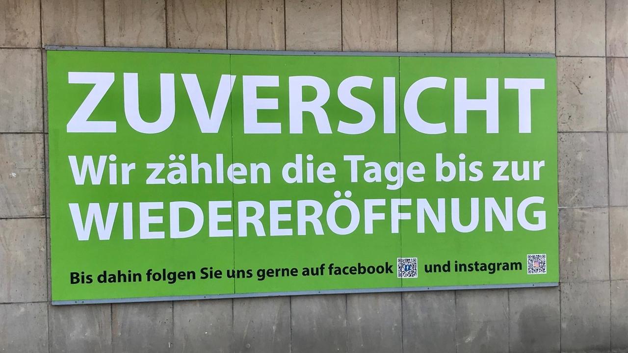 Auf einem Plakat an den Uckermärkischen Bühnen Schwedt (ubs) hängt ein grünes Plakat, auf dem in weißer Schrift geschrieben steht: "Zuversicht. Wir zählen die Tage bvis zur Wiedereröffnung." Darunter steht in schwarzer Schrift: Bis dahin folgen Sie uns gerne auf Facebook und Instagram"