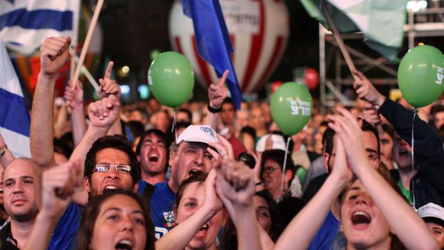 Eine Menschenmenge mit grünen Luftballons und israelischen Flaggen.