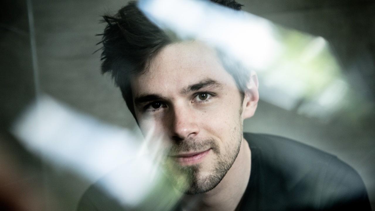 Ein Mann mit strubbeligen, dunklen Haaren schaut in die Kamera. Ein Mann mit strubbeligen, dunklen Haaren schaut in die Kamera.