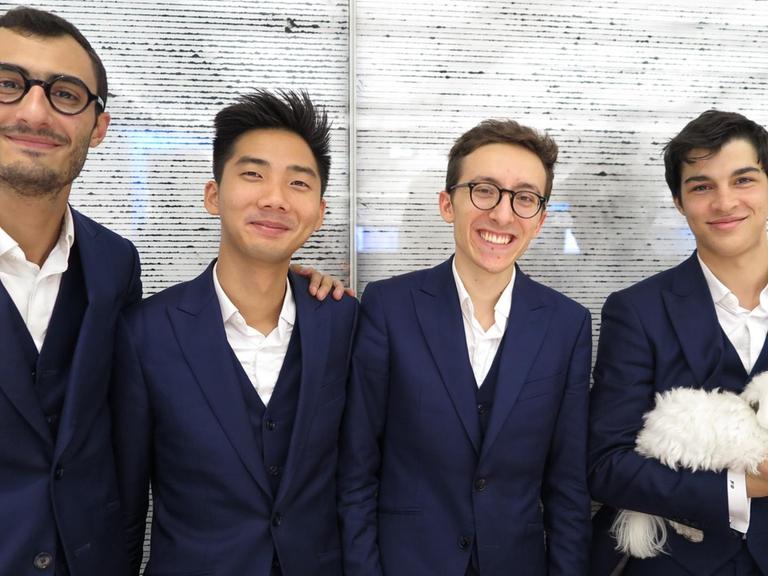 Die Musiker des Arod Quartetts stehen nebeneinander im Deutschlandfunk Foyer, lachen in die Kamera. Mit dabei: ihr Schoßhündchen.