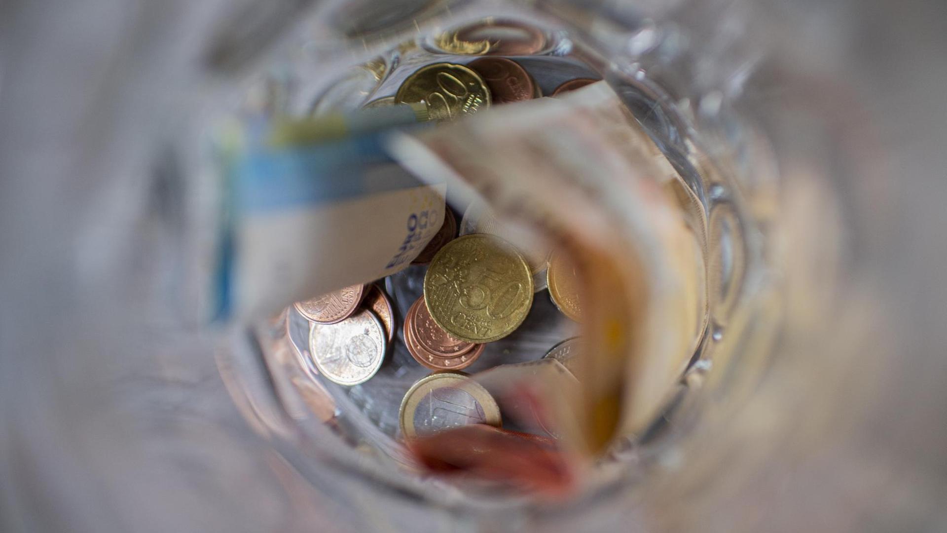 Münzgeld und Scheingeld liegen in einem Glasbehälter. Münzgeld und Scheingeld liegen in einem Glasbehälter.