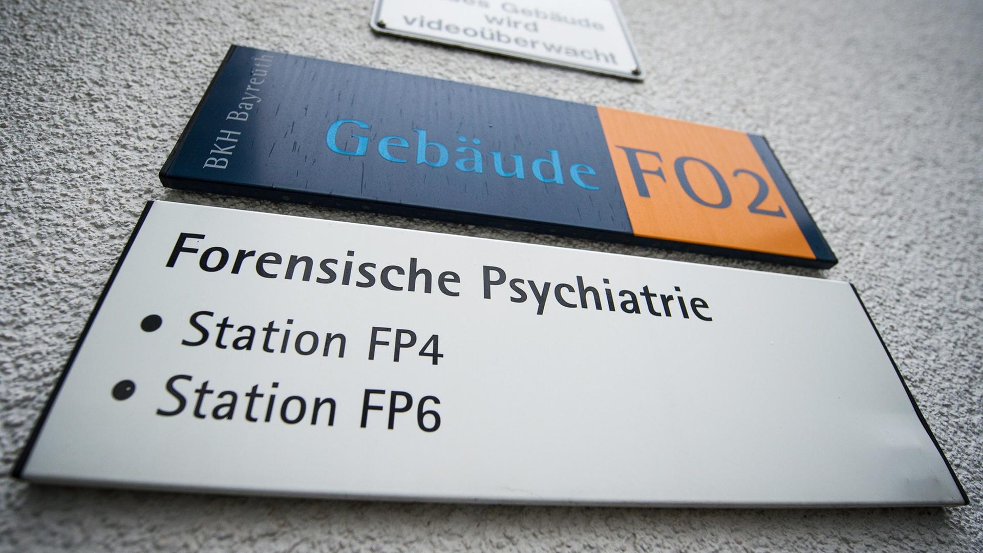 Ein Schild mit der Aufschrift "Forensische Psychiatrie" hängt an einem Stationsgebäude des Bezirkskrankenhauses in Bayreuth.