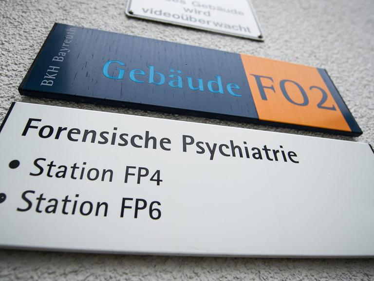 Ein Schild mit der Aufschrift "Forensische Psychiatrie" hängt an einem Stationsgebäude des Bezirkskrankenhauses in Bayreuth.
