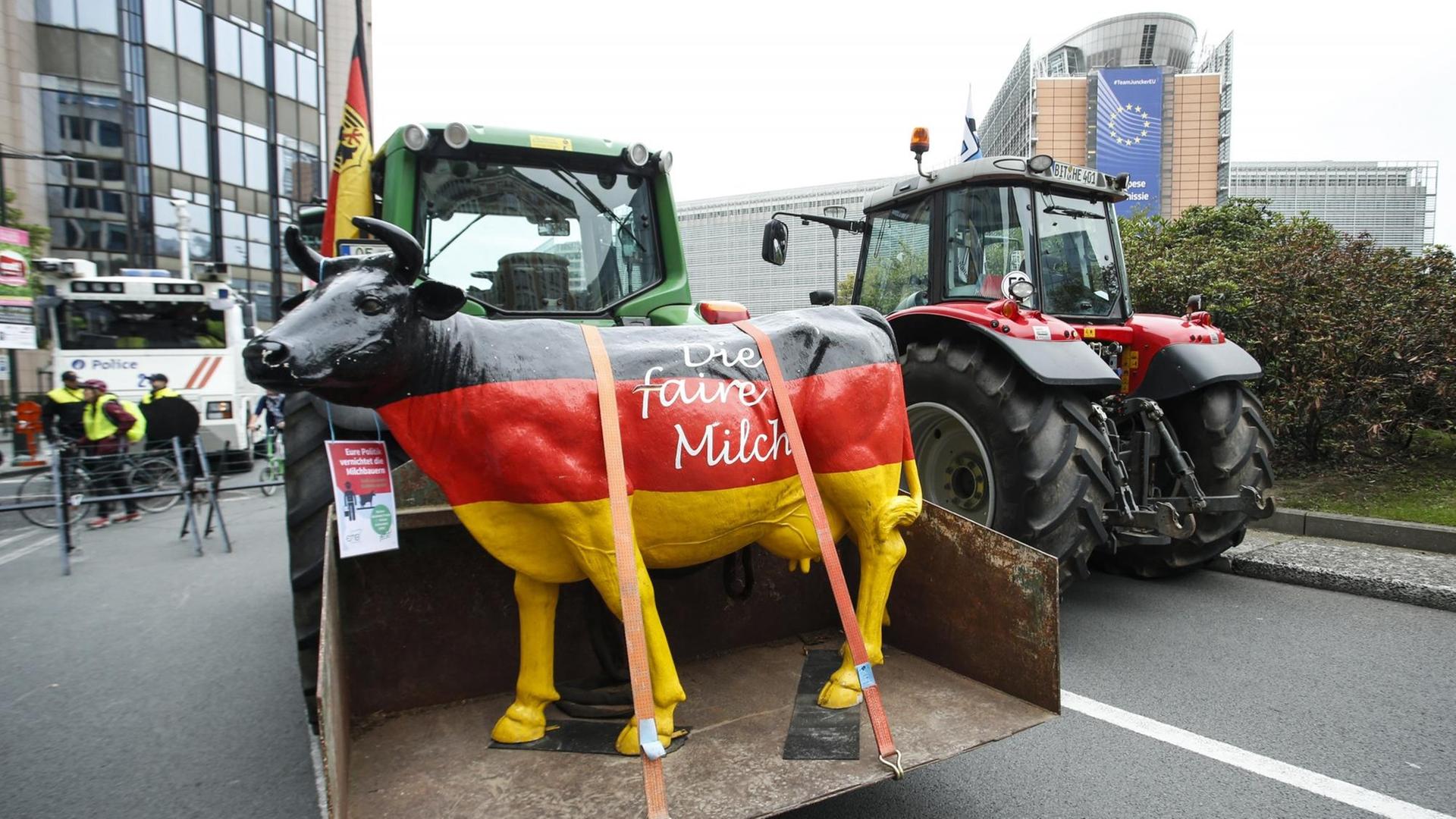 Ein Traktor fährt eine Kuh-Statue in schwarz-rot-gold durch das EU-Viertel in Brüssel. Auf der Kuh steht "Die faire Milch": Ein Traktor fährt eine Kuh-Statue in schwarz-rot-gold durch das EU-Viertel in Brüssel. Auf der Kuh steht "Die faire Milch":