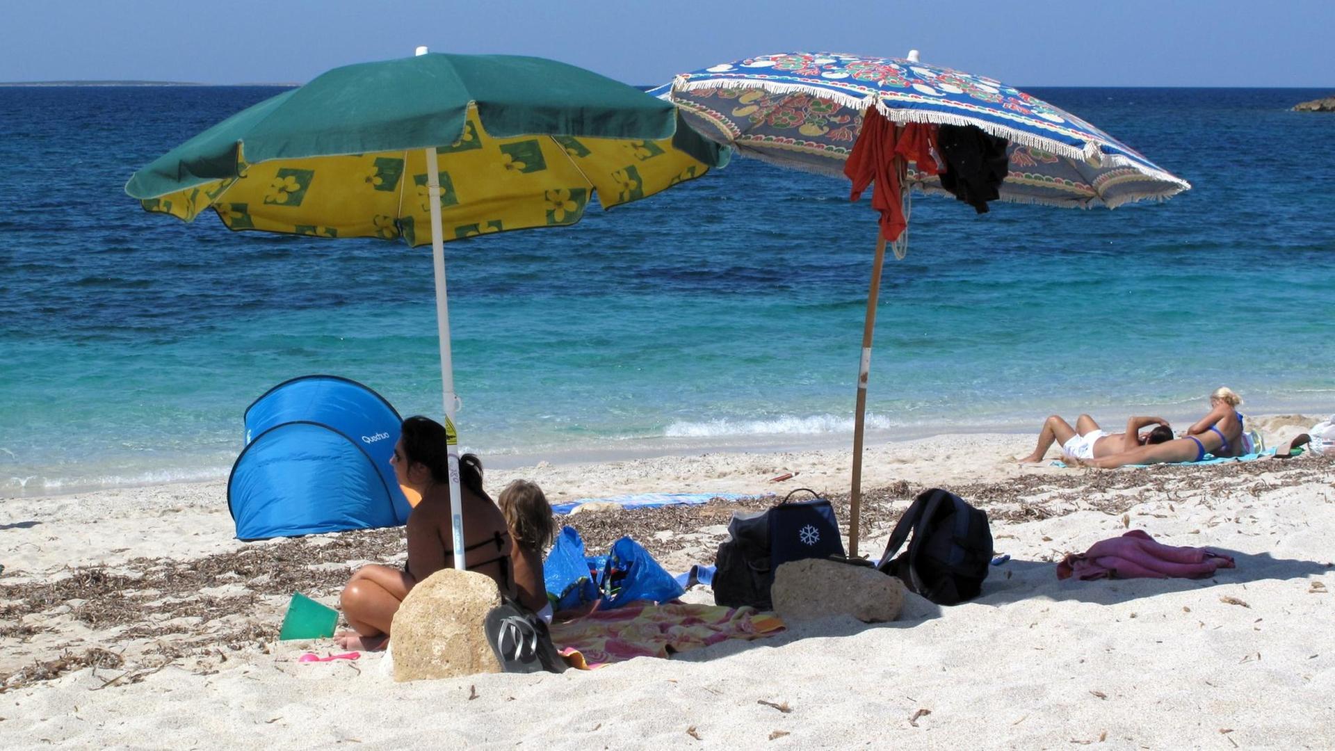 Touristen erholen sich am Strand an der Westküste Sardiniens