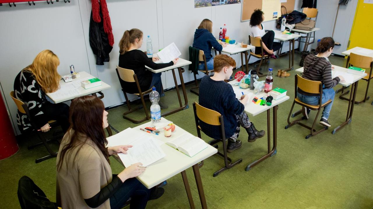 Die Schüler sitzen an einzeln aufgestellten Tischen und arbeiten an ihren Aufgaben. Die Schüler sitzen an einzeln aufgestellten Tischen und arbeiten an ihren Aufgaben.