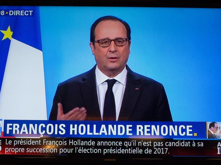 Der französische Präsident Francois Hollande ist auf einem Fernsehbildschirm hinter einem Schreibtisch zu sehen. Er trägt einen dunklen Anzug.