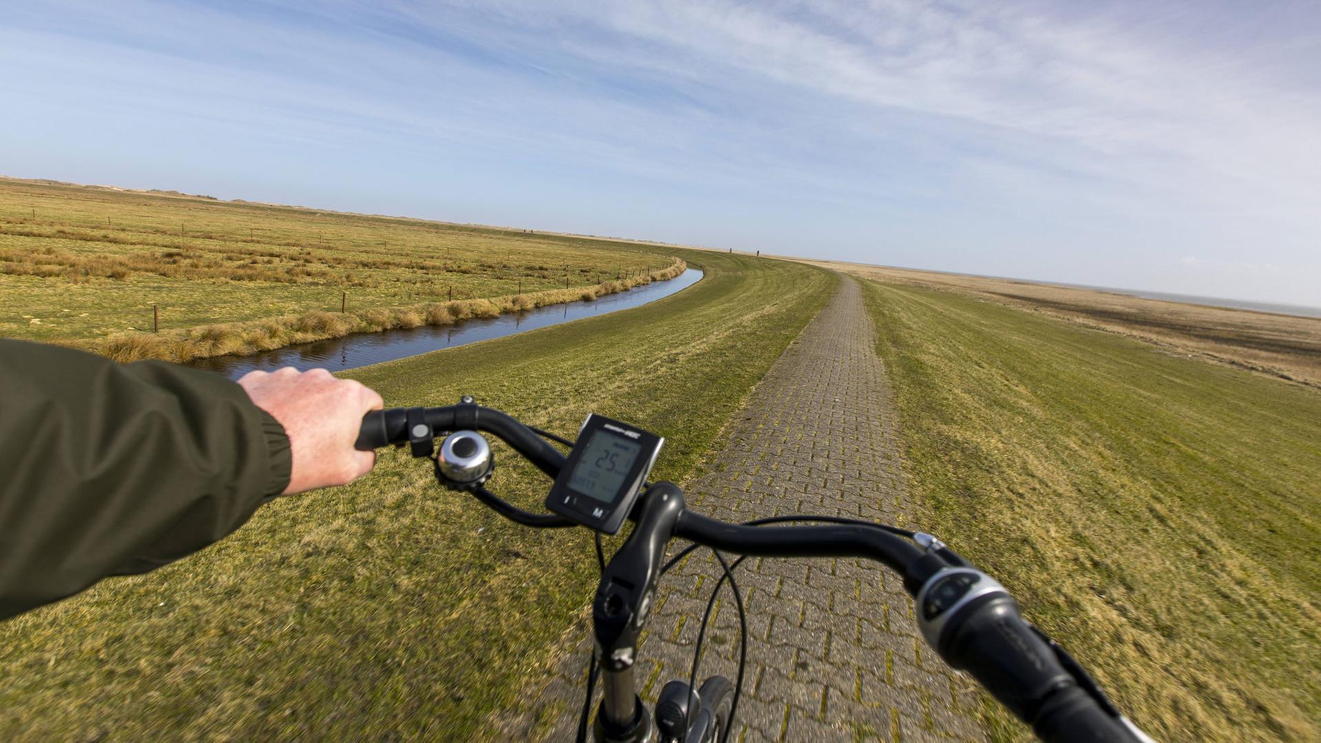 Blick eines Radfahrers bei einer Tour auf einem Deich bei Norderney. Blick eines Radfahrers bei einer Tour auf einem Deich bei Norderney.