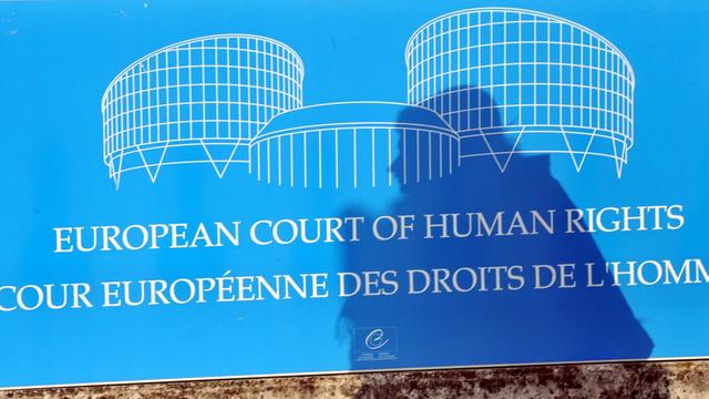 Der Schatten einer Frau fällt auf ein Schild vor dem Gebäude des Europäischen Gerichtshofs für Menschenrechte (EGMR) in Straßburg.
