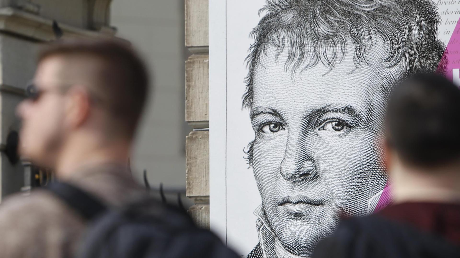 Menschen gehen an einer Plakatwand mit einem Bild des preußischen Forschers, Geographen und Naturforschers Alexander von Humboldt vorbei. Menschen gehen an einer Plakatwand mit einem Bild des preußischen Forschers, Geographen und Naturforschers Alexander von Humboldt vorbei.