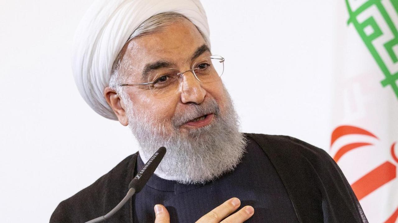 Der Iranische Präsident Hassan Rohani steht auf einer Bühne und spricht ins Mikrofon, seine rechte Hand liegt auf seinem Herzen. Der Iranische Präsident Hassan Rohani steht auf einer Bühne und spricht ins Mikrofon, seine rechte Hand liegt auf seinem Herzen.