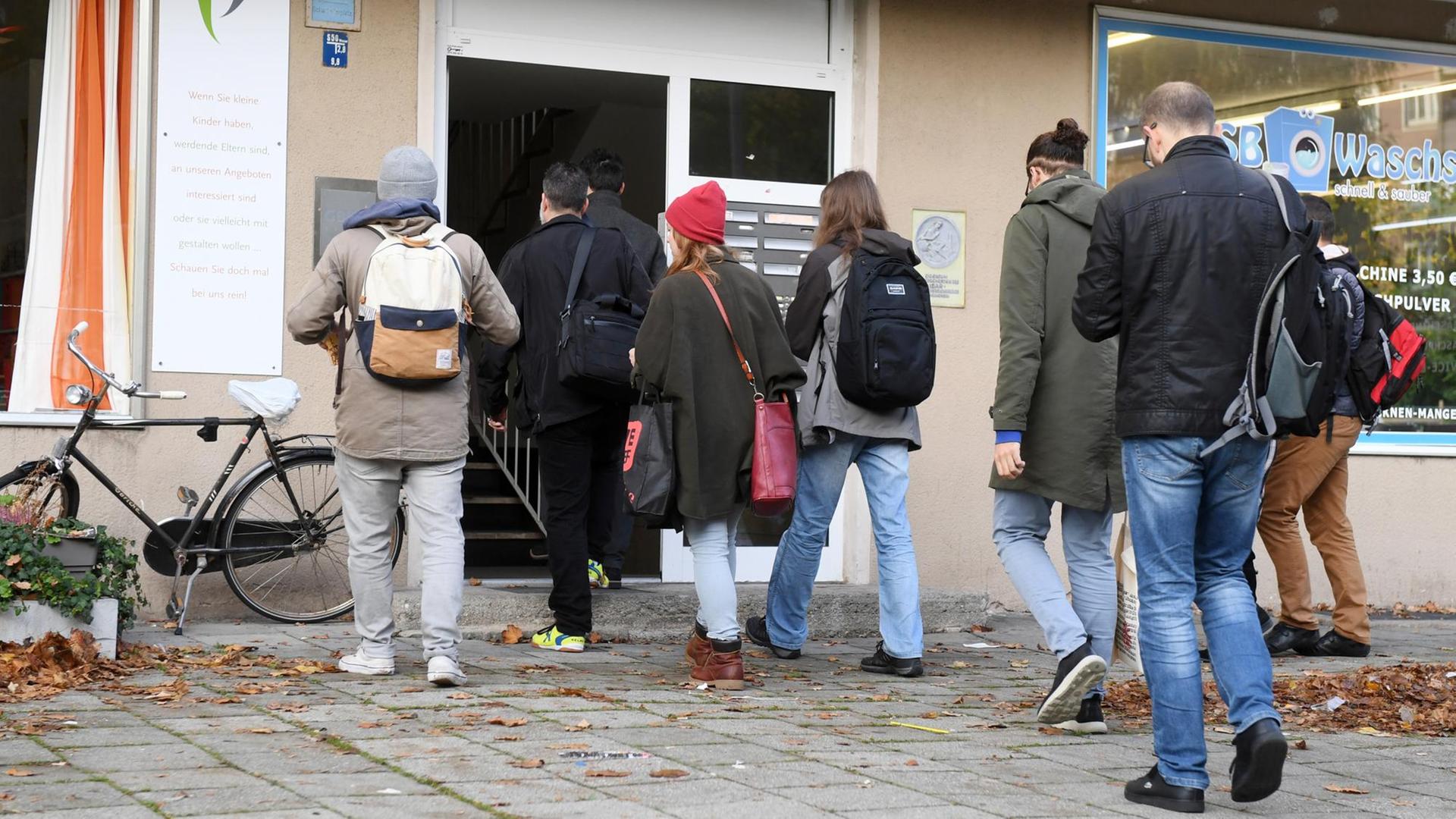 Interessenten betreten am 11.10.2017 in München (Bayern) ein Mehrfamilienhaus um an einer Wohungsbesichtigung teilzunehmen. Interessenten betreten am 11.10.2017 in München (Bayern) ein Mehrfamilienhaus um an einer Wohungsbesichtigung teilzunehmen.