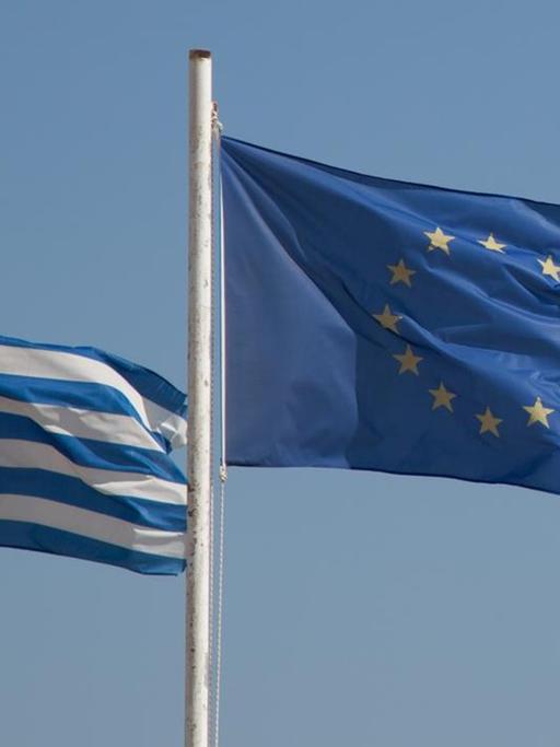 EU-Flagge und Griechenland-Flagge vor blauem Himmel