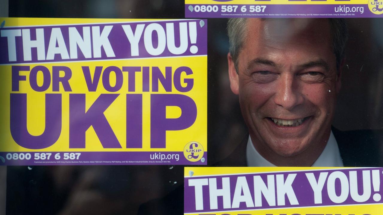 UKIP-Parteichef Nigel Farage schaut durch ein Fenster des Wahlkampfbüros in Clacton-on-Sea, neben, über und unter ihm Plakate mit der Aufschrift "Thank you for voting UKIP"