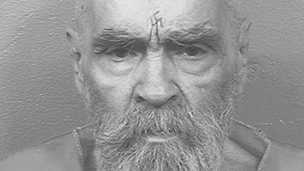 Charles Manson steht vor einer weißen Wand, auf der Stirn trägt er ein Hakenkreuz-Tattoo Charles Manson steht vor einer weißen Wand, auf der Stirn trägt er ein Hakenkreuz-Tattoo