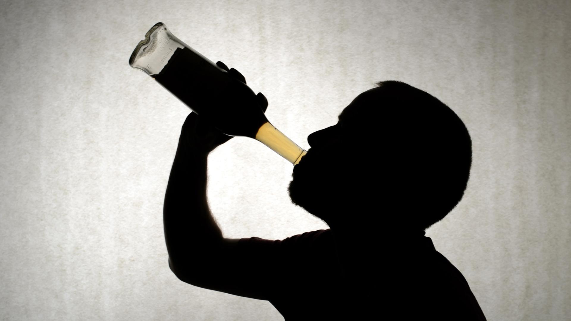 Ein Mann trinkt aus einer Flasche Whisky. Ein Mann trinkt aus einer Flasche Whisky.