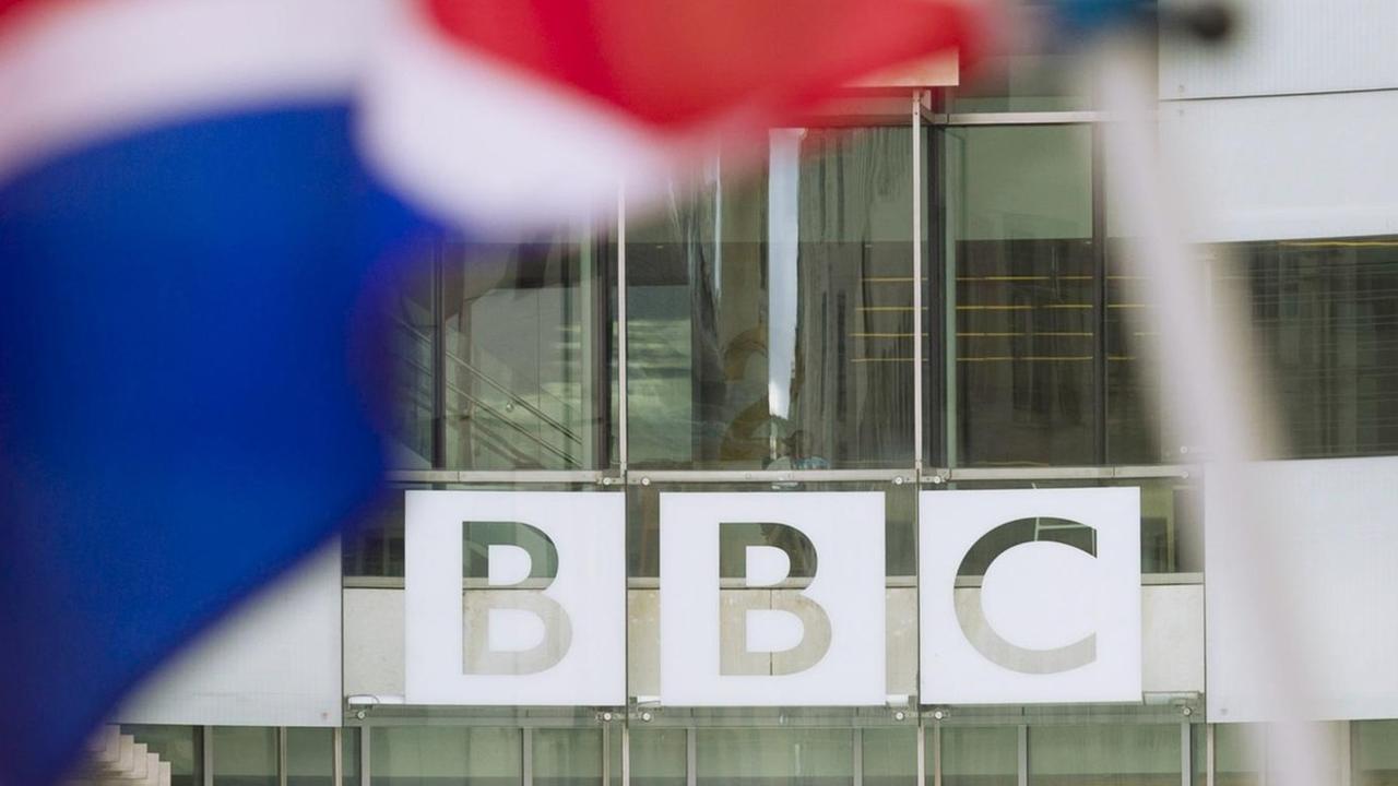 Eine Flagge von Großbritanien weht vor dem Schriftzug des Senders BBC Eine Flagge von Großbritanien weht vor dem Schriftzug des Senders BBC