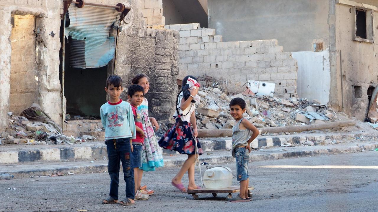 Kinder auf einer Straße mit Wasserbehältern in Tadmur, Provinz Homs