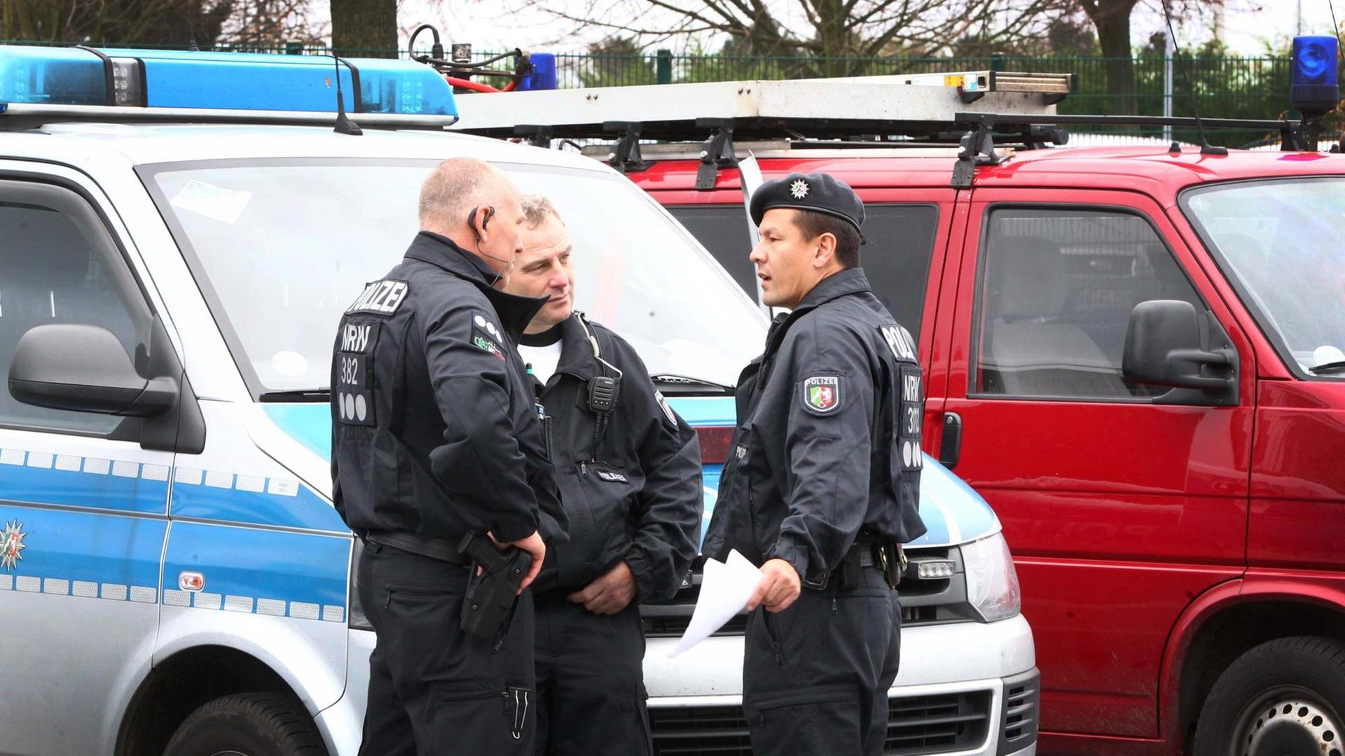 Polizisten stehen vor Einsatzfahrzeugen Polizisten stehen vor Einsatzfahrzeugen
