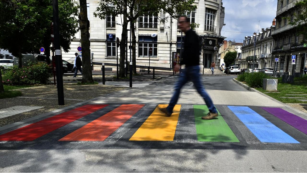 Ein Passant überquert einen Zebrastreifen in den Farben des Regenbogens. Ein Passant überquert einen Zebrastreifen in den Farben des Regenbogens.
