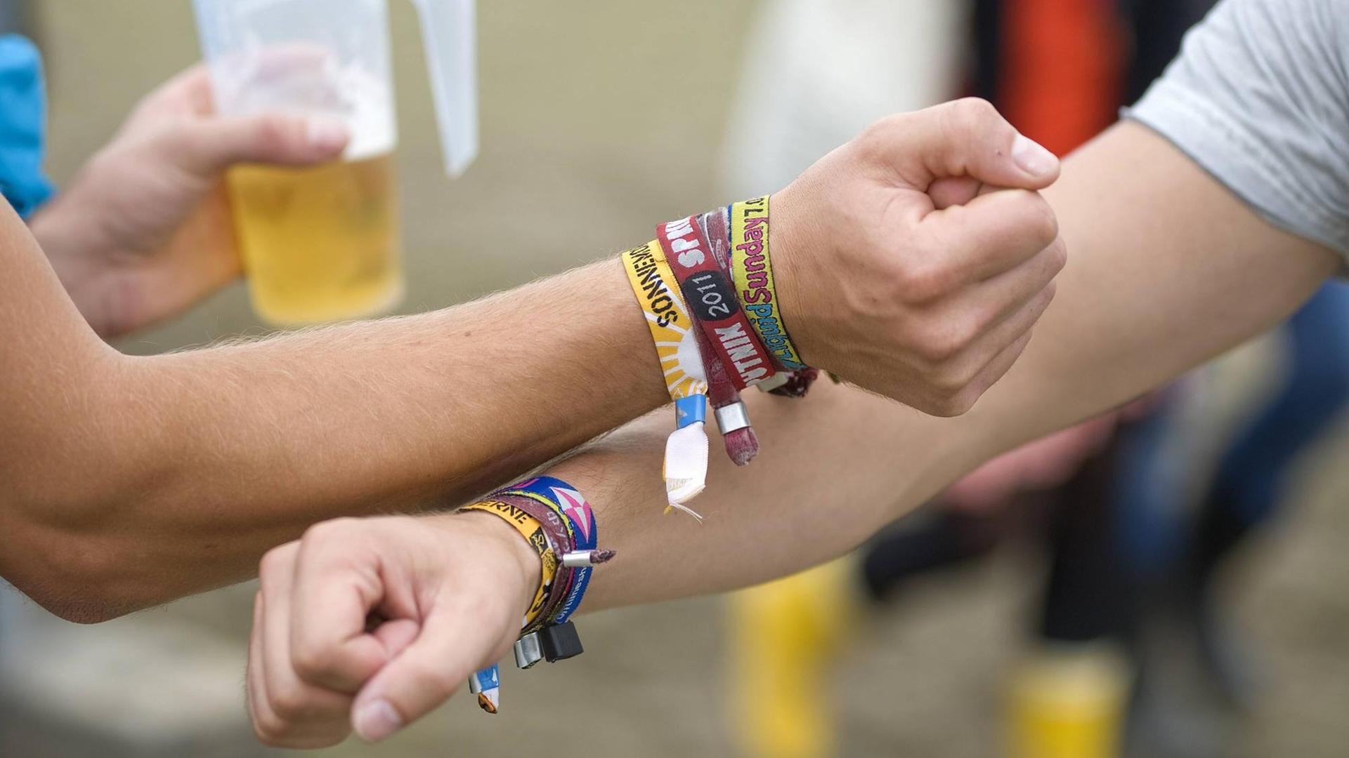 Zwei männliche Besucher des SonneMondSterne Musikfestivals an der Bleilochtalsperre im thüringischen Saalburg zeigen ihre Unterarme mit Bändchen von diversen Musikfestivals, die sie in diesem Jahr besucht haben. Zwei männliche Besucher des SonneMondSterne Musikfestivals an der Bleilochtalsperre im thüringischen Saalburg zeigen ihre Unterarme mit Bändchen von diversen Musikfestivals, die sie in diesem Jahr besucht haben.