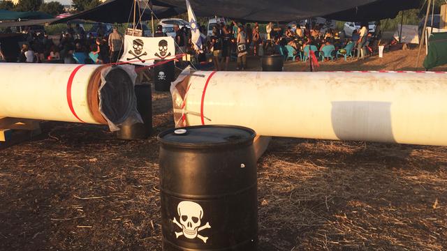 Gegner eines Raffinerie-Baus in Israel protestieren mit Totenkopfsymbolen an einer Pipeline