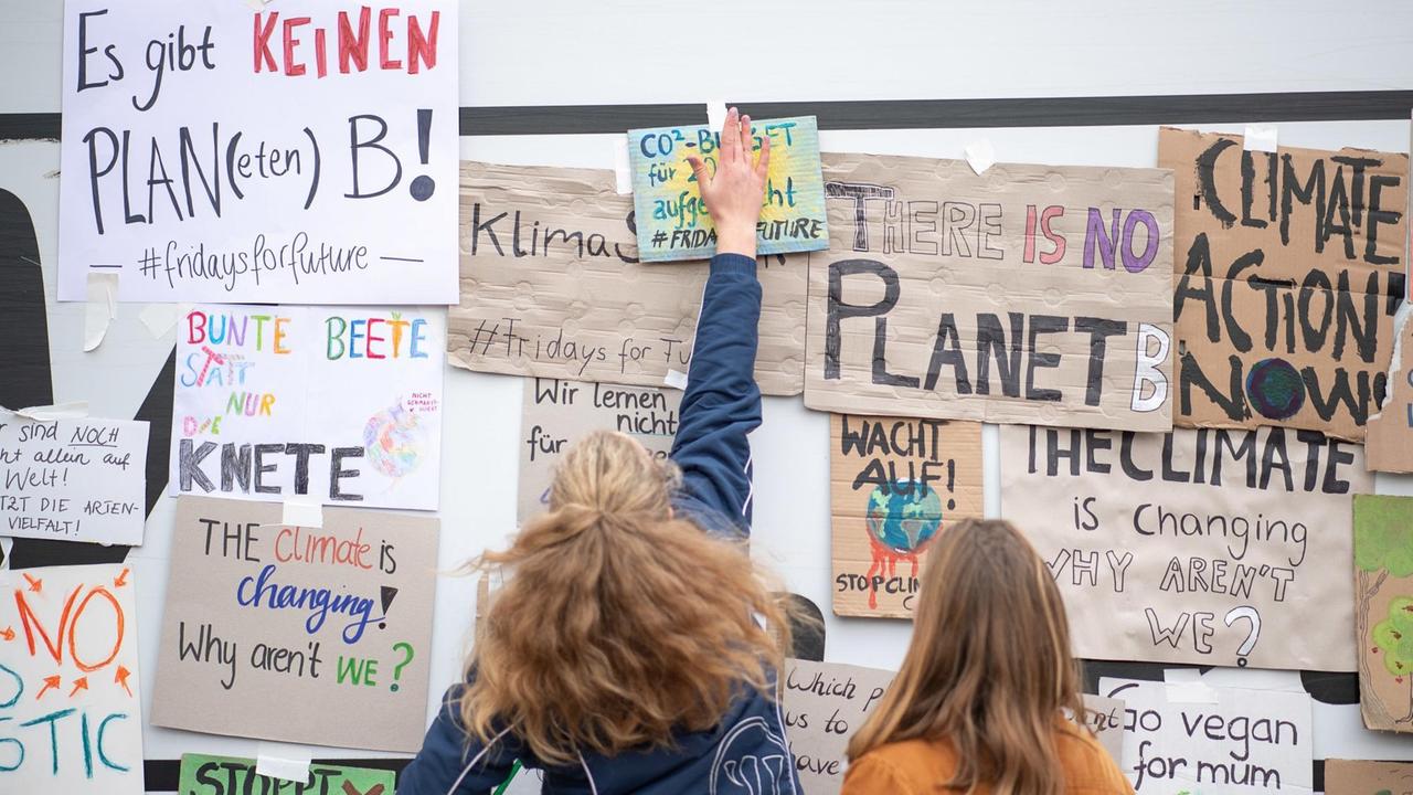 18.01.2019, Baden-Württemberg, Stuttgart: Zwei Schülerinnen kleben während einer Demonstration von Schülern gegen den Klimawandel Plakate an eine Wand. Die Aktion steht unter dem Motto "Fridays for future". 18.01.2019, Baden-Württemberg, Stuttgart: Zwei Schülerinnen kleben während einer Demonstration von Schülern gegen den Klimawandel Plakate an eine Wand. Die Aktion steht unter dem Motto "Fridays for future".
