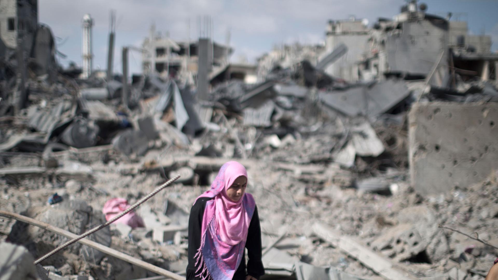 Eine palästinensische Frau läuft in Trümmern in Gaza Stadt umher. Eine palästinensische Frau läuft in Trümmern in Gaza Stadt umher.