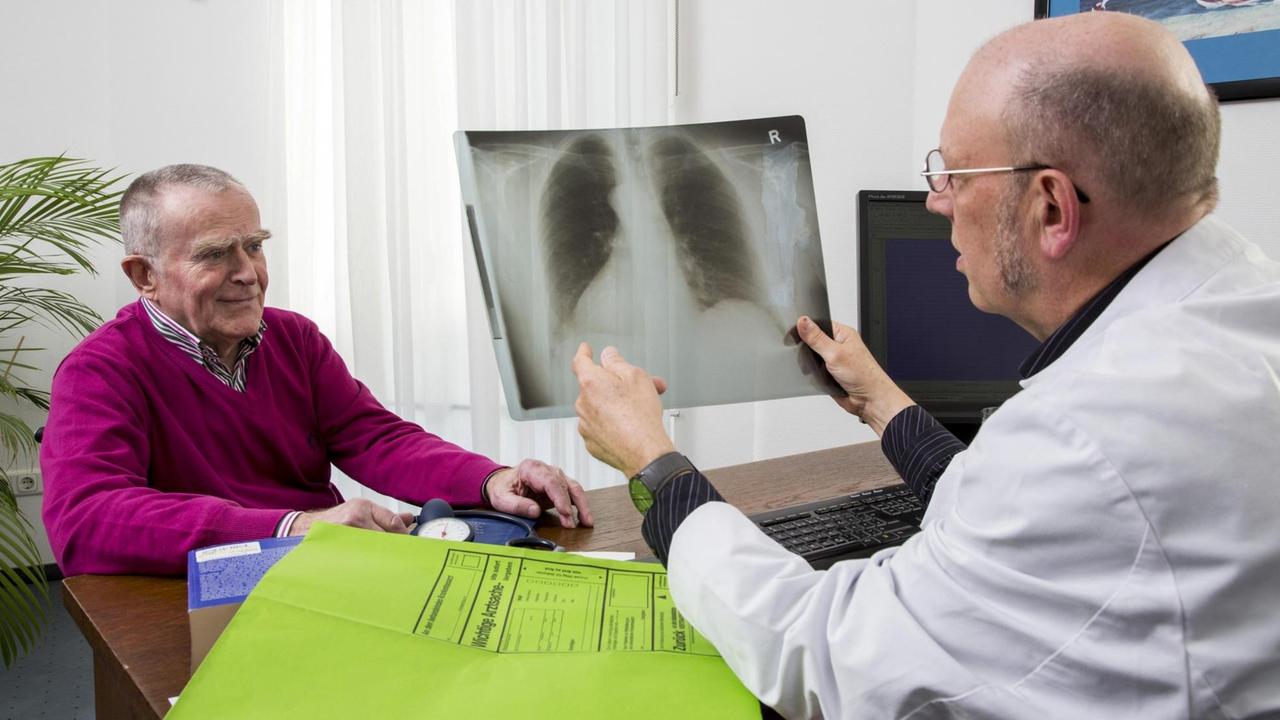 Arztpraxis, älterer Patient im Gespräch mit seinem Hausarzt, Besprechung einer Röntgenuntersuchung der Lunge,