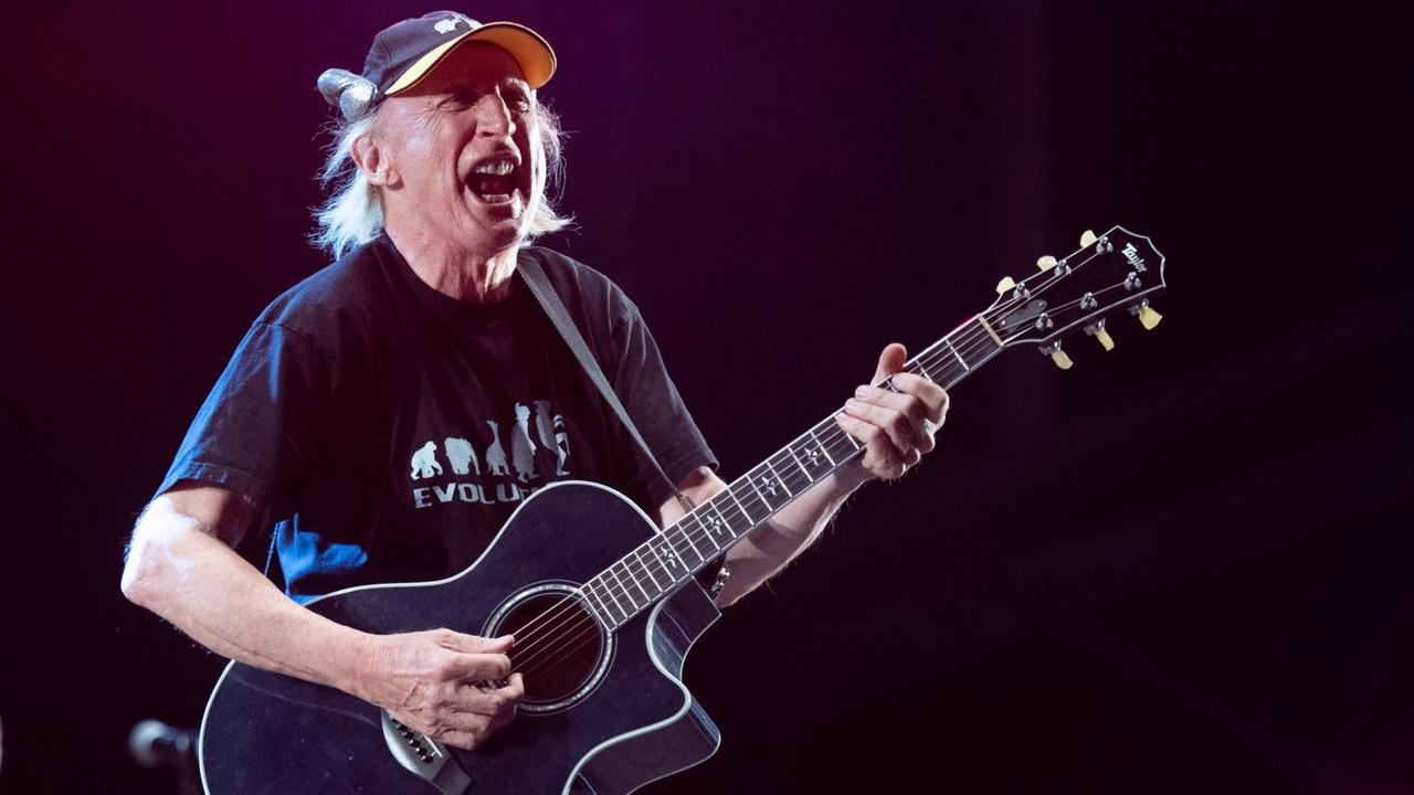 Waalkes läuft mit schwarzer Gitarre in der Hand und verzerrtem Gesicht vor schwarzem Hintergrund über die Bühne. Waalkes läuft mit schwarzer Gitarre in der Hand und verzerrtem Gesicht vor schwarzem Hintergrund über die Bühne.