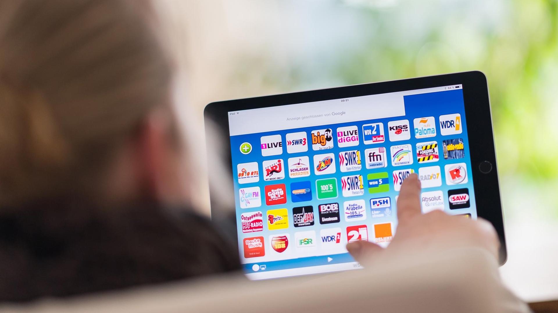 Eine Frau wählt am 03.03.2017 in Warendorf (Nordrhein-Westfalen) auf einem iPad mit einer Radio App einen Sender aus. Während man früher Radiosender ausschließlich über ein Radiogerät hörte, nutzt man heute auch Smartphone und iPads zum Radio hören. Eine Frau wählt am 03.03.2017 in Warendorf (Nordrhein-Westfalen) auf einem iPad mit einer Radio App einen Sender aus. Während man früher Radiosender ausschließlich über ein Radiogerät hörte, nutzt man heute auch Smartphone und iPads zum Radio hören.