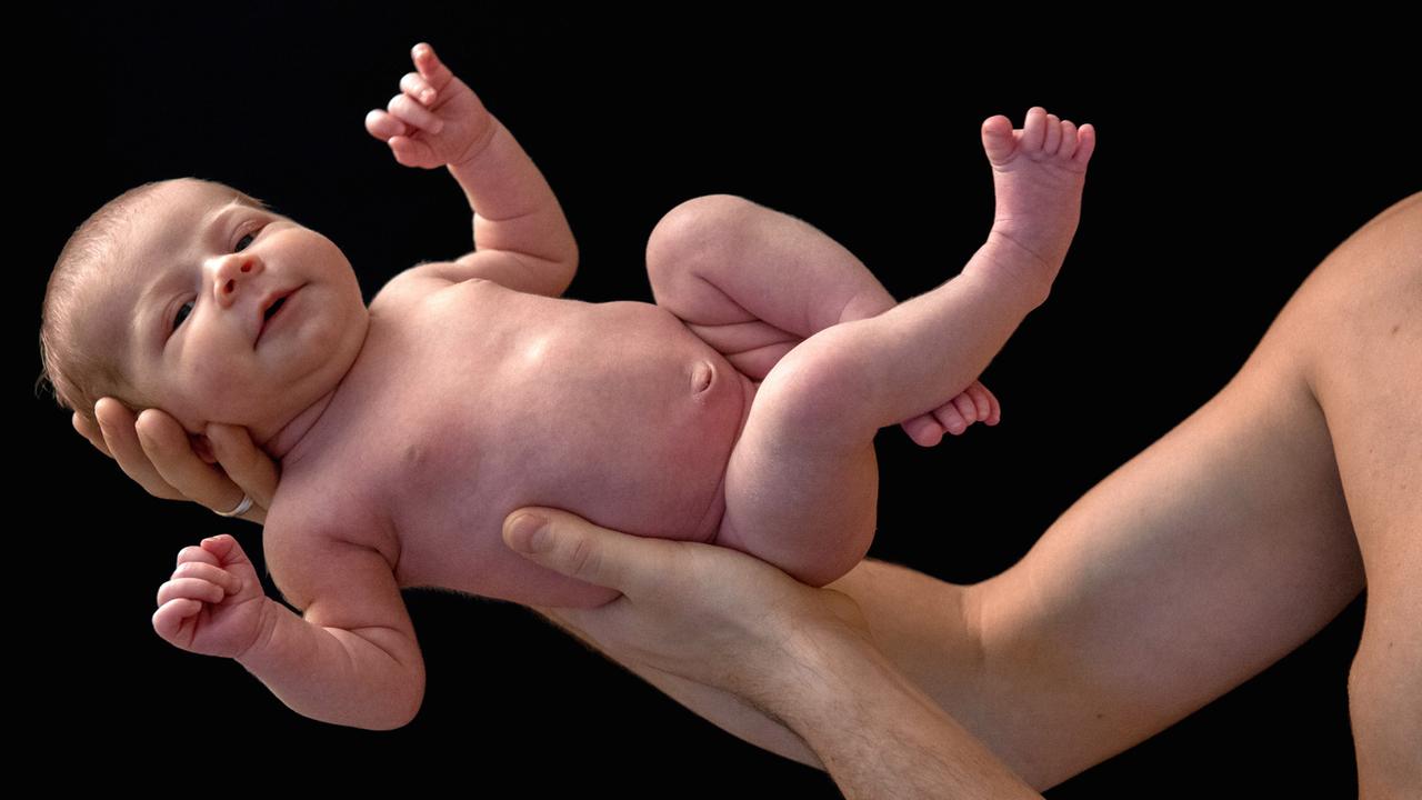 Ein junger Mann hält stolz seine neu geborene kleine Tochter in den Armen. Ein junger Mann hält stolz seine neu geborene kleine Tochter in den Armen.