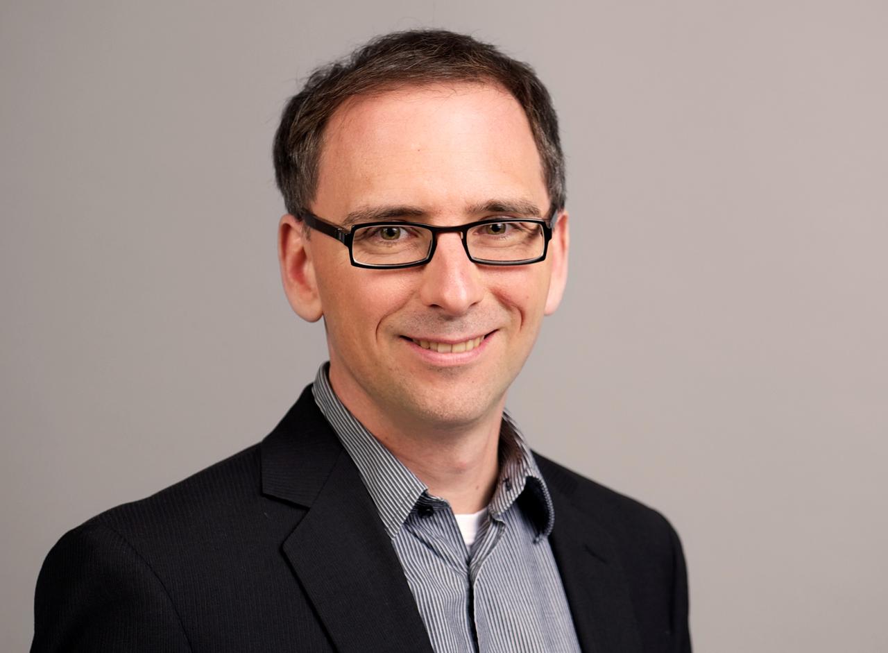 David Lauer steht für ein Porträt-Bild vor einem grauen Hintergrund. David Lauer steht für ein Porträt-Bild vor einem grauen Hintergrund.
