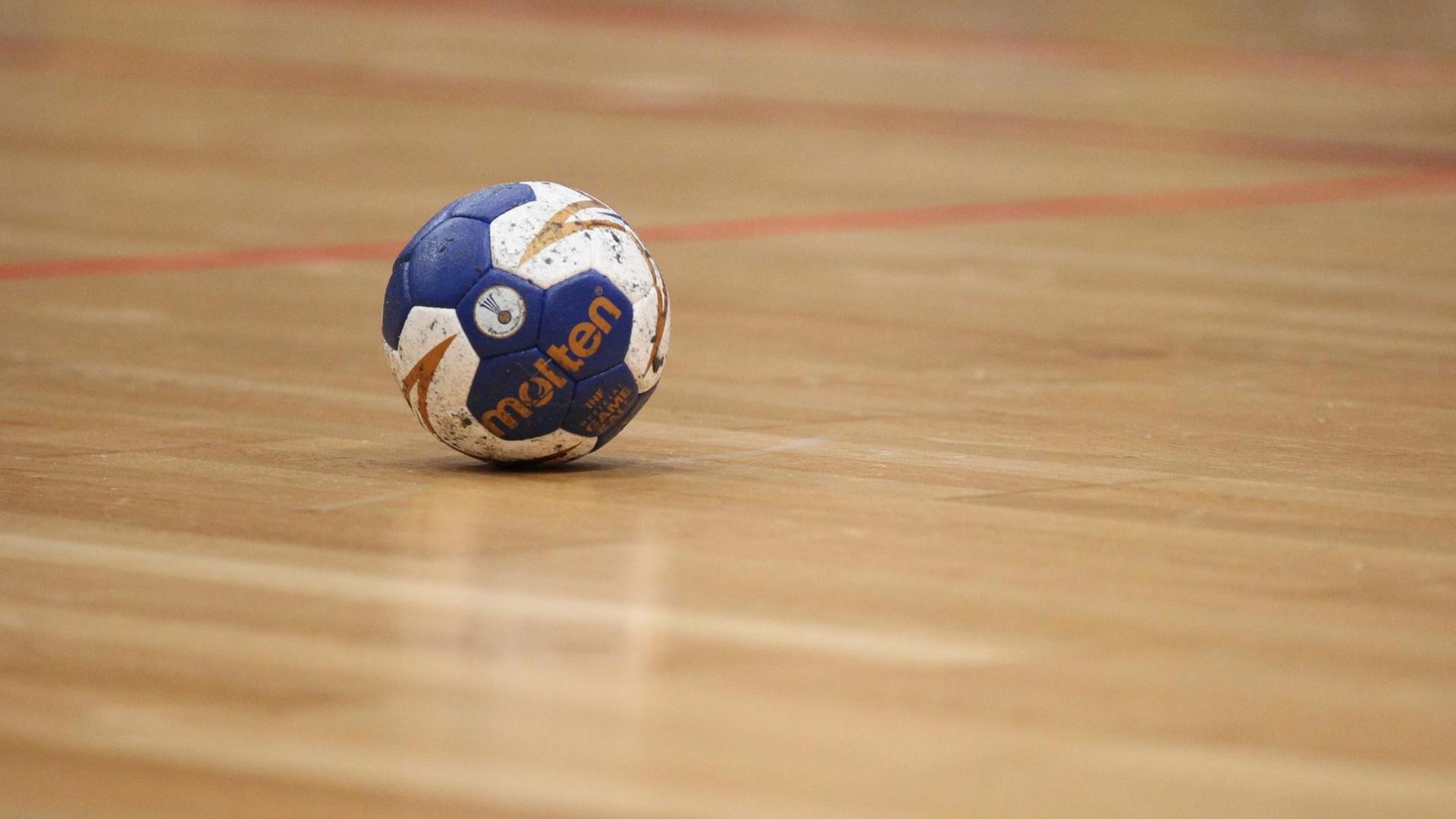 Ein Handball liegt auf den Hallenboden. Ein Handball liegt auf den Hallenboden.