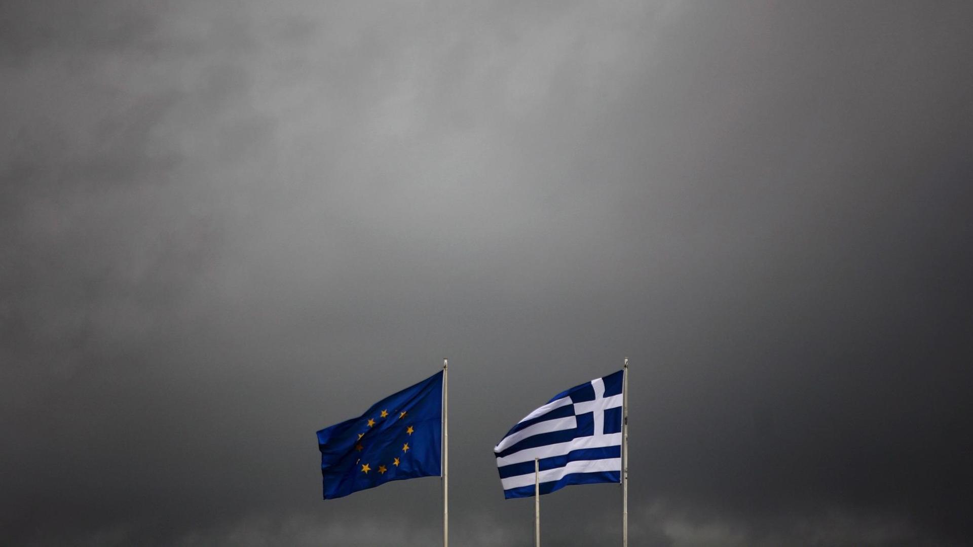 Die griechische und europäische Flagge flattern im Wind eines Gewitters.