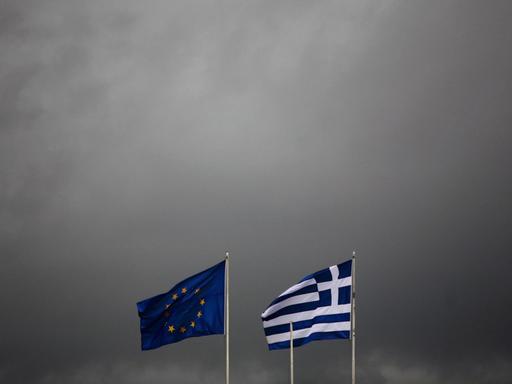 Die griechische und europäische Flagge flattern im Wind eines Gewitters.