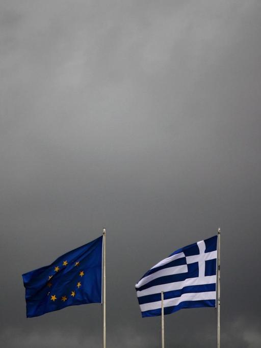 Die griechische und europäische Flagge flattern im Wind eines Gewitters.
