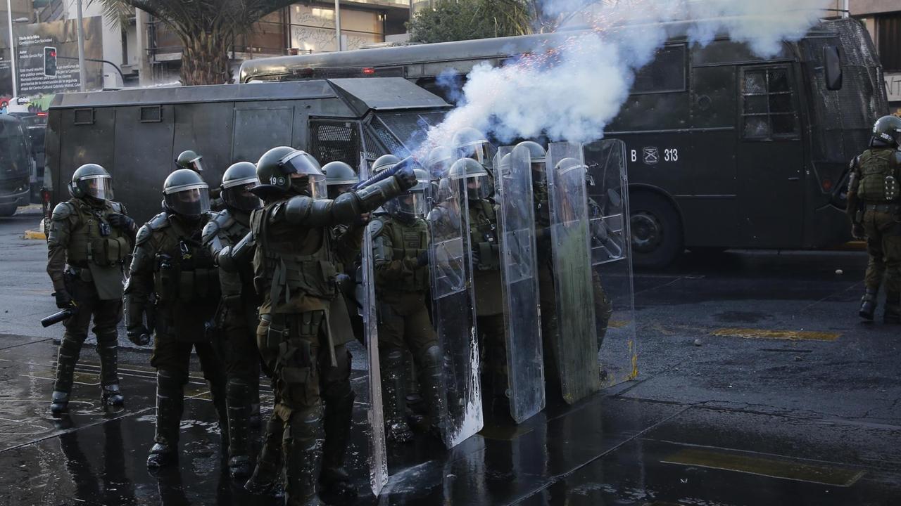 Eine Gruppe von chilenische Bereitschaftspolizisten schießen Tränengas auf Demonstranten. Eine Gruppe von chilenische Bereitschaftspolizisten schießen Tränengas auf Demonstranten.