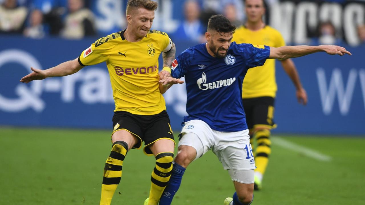Marco Reus (BVB) in einer Aktion gegen Daniel Caligiuri (Schalke). Marco Reus (BVB) in einer Aktion gegen Daniel Caligiuri (Schalke).