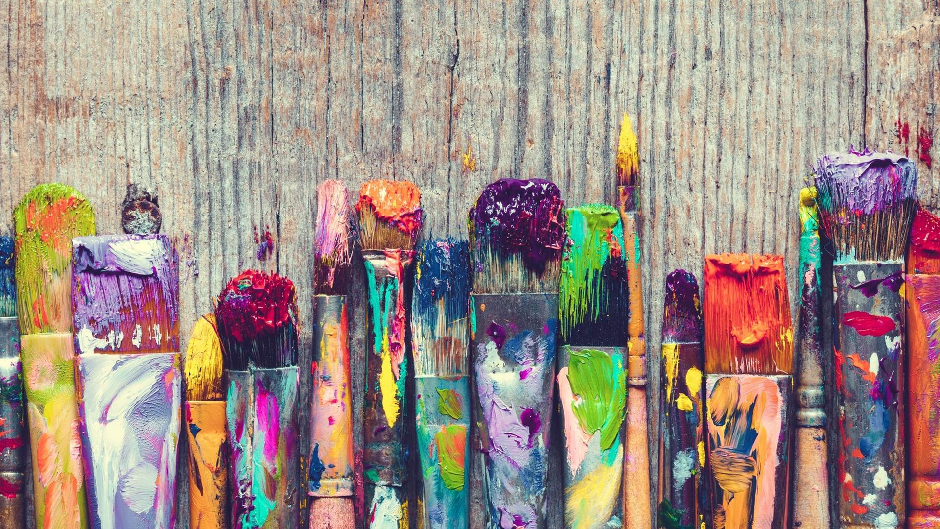 Eine Palette an bunten Pinseln, die mit allen regenbogenfarben beschmiert sind. Eine Palette an bunten Pinseln, die mit allen regenbogenfarben beschmiert sind.