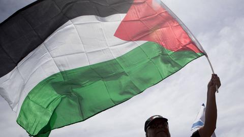 Ein Mann schwenkt eine palästinensische Flagge.