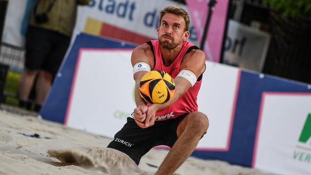 Alexander Walkenhorst kniet im Sand und baggert den Ball.