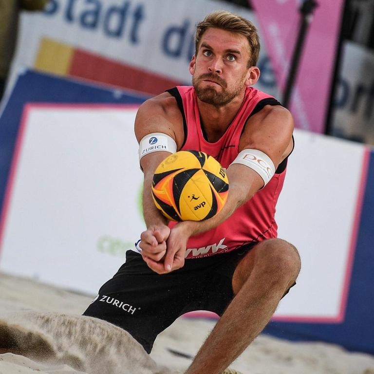 Alexander Walkenhorst kniet im Sand und baggert den Ball.