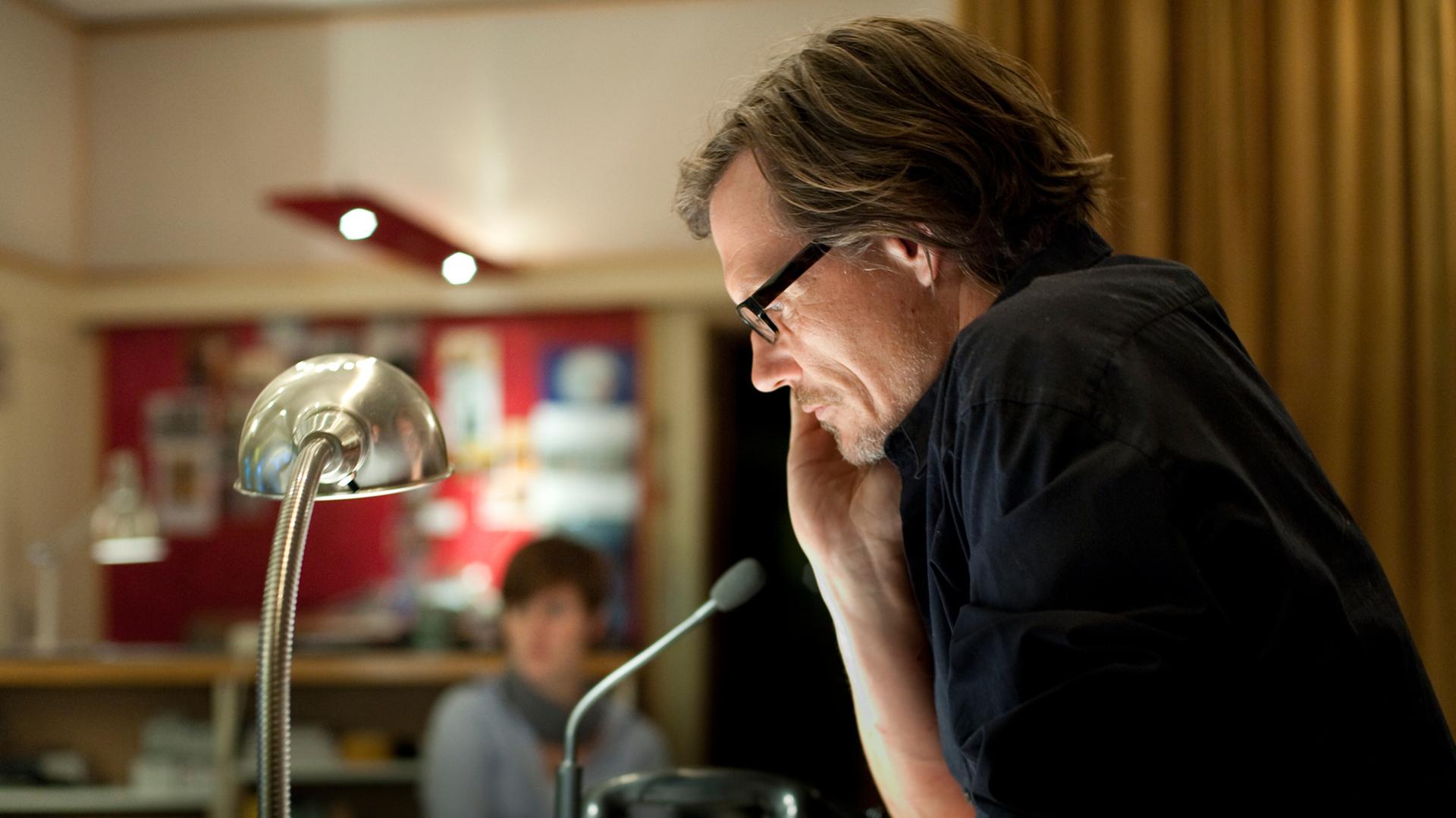 Der Regisseur Alexander Schuhmacher sitzt bei einer Studioaufnahme am Tisch.  