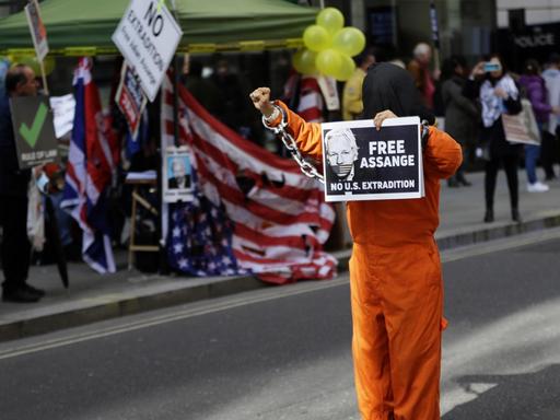 Ein maskierter Demonstrant hat sich als Gefängnisinsasse verkleidet und hält am 1. Oktober 2020 in London ein Schild mit dem Konterfei von julian Assange und der Aufschrift "Free Assange" in der Hand.