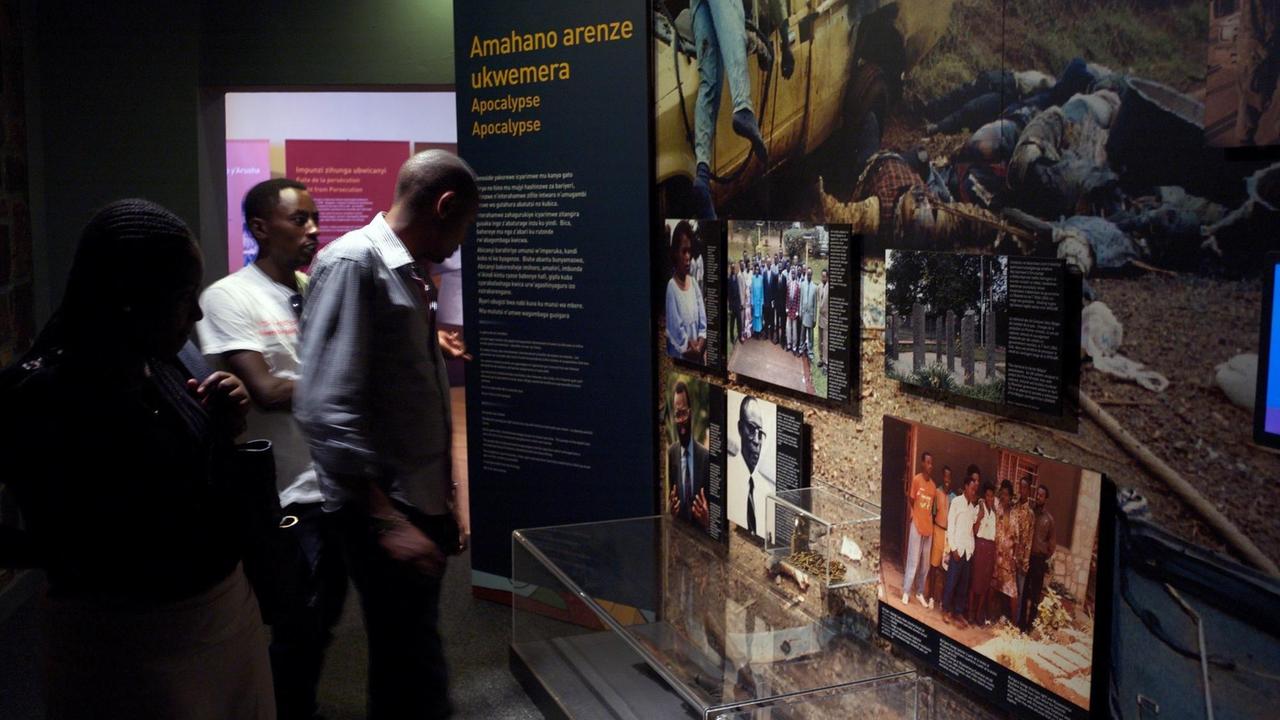 Drei Besucheri*innen schauen sich Ausstellungstafeln im Kigali Genocide Memorial an Drei Besucheri*innen schauen sich Ausstellungstafeln im Kigali Genocide Memorial an