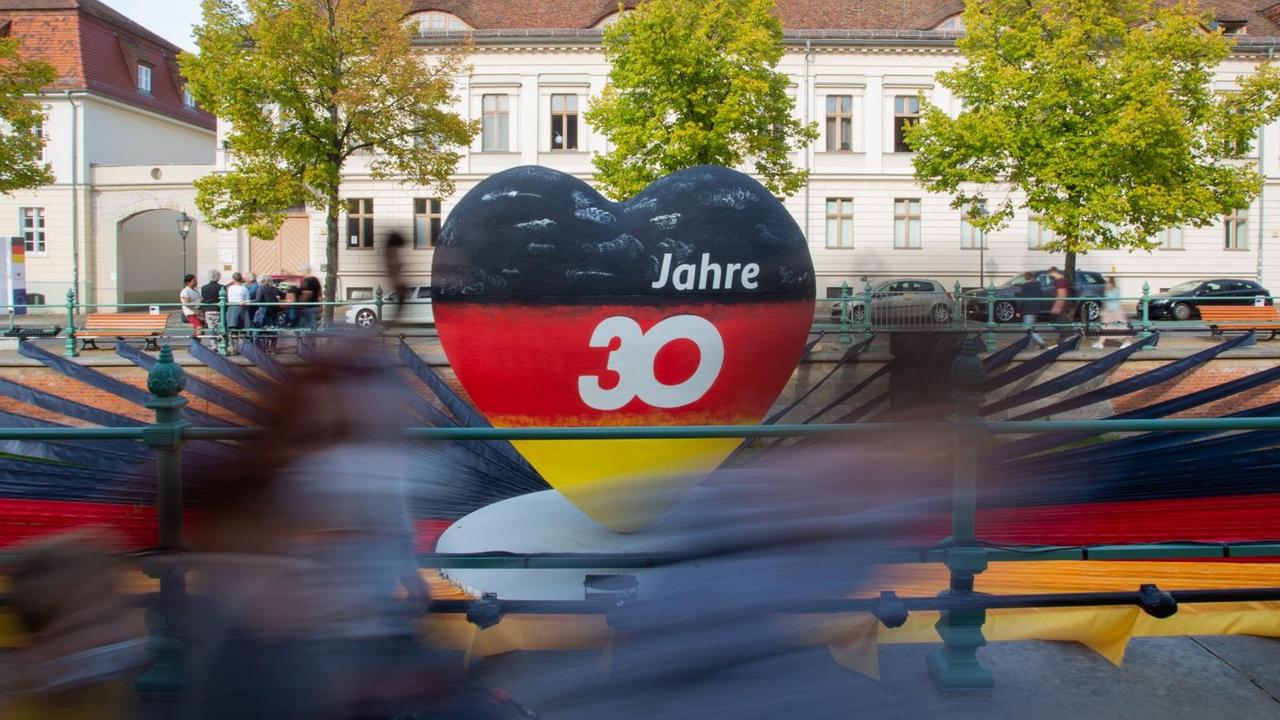 Passanten gehen an einem schwarz-rot-goldenen Herz mit der Aufschrift "30 Jahre" vorbei. Potsdam als Brandenburger Landeshauptstadt war in diesem Jahr Gastgeber der zentralen Feierlichkeiten zum Tag der Deutschen Einheit. Passanten gehen an einem schwarz-rot-goldenen Herz mit der Aufschrift "30 Jahre" vorbei. Potsdam als Brandenburger Landeshauptstadt war in diesem Jahr Gastgeber der zentralen Feierlichkeiten zum Tag der Deutschen Einheit.