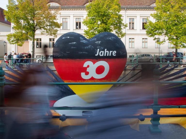 Passanten gehen an einem schwarz-rot-goldenen Herz mit der Aufschrift "30 Jahre" vorbei. Potsdam als Brandenburger Landeshauptstadt war in diesem Jahr Gastgeber der zentralen Feierlichkeiten zum Tag der Deutschen Einheit.
