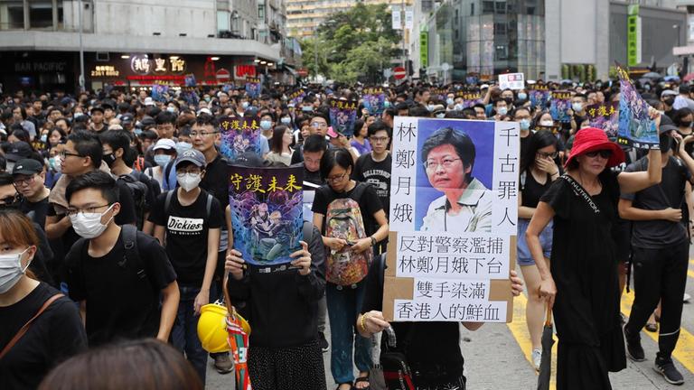 Ein Protestierer hält während einer Demonstration durch das Viertel Mong Kok ein Schild mit der Aufschrift "Carrie Lam von der Geschichte verurteilt" hoch.