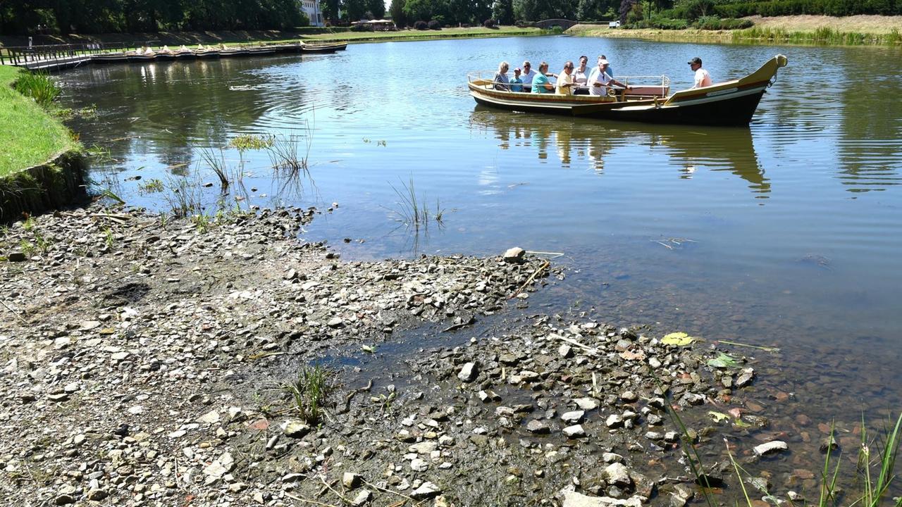 23.07.2019, Sachsen-Anhalt, Wörlitz: Im Wörlitzer Park fährt eine Gondel auf dem Großen See hinter einer Uferzone, die nicht mehr von Wasser bedeckt ist. Der Wasserspiegel ist wegen der Wetterlage bereits um einen halben Meter abgesunken. Damit können die Gondeln mit den Besuchern den Großen See, aber nicht mehr die Kanäle befahren. Foto: Waltraud Grubitzsch/dpa-Zentralbild/dpa | Verwendung weltweit 23.07.2019, Sachsen-Anhalt, Wörlitz: Im Wörlitzer Park fährt eine Gondel auf dem Großen See hinter einer Uferzone, die nicht mehr von Wasser bedeckt ist. Der Wasserspiegel ist wegen der Wetterlage bereits um einen halben Meter abgesunken. Damit können die Gondeln mit den Besuchern den Großen See, aber nicht mehr die Kanäle befahren. Foto: Waltraud Grubitzsch/dpa-Zentralbild/dpa | Verwendung weltweit